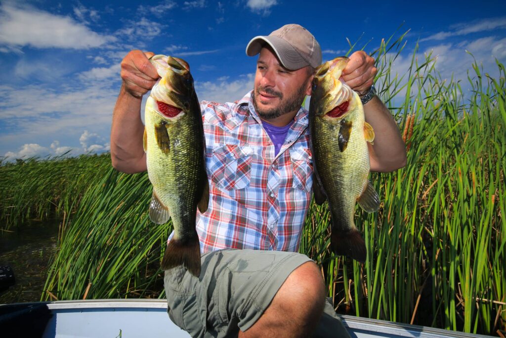 man holding two largemouth bass